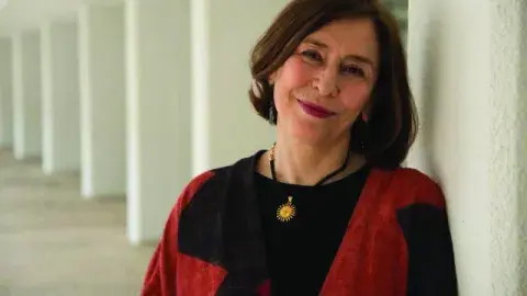 Azar Nafisi in a red and black sweater leaning against a collomnade