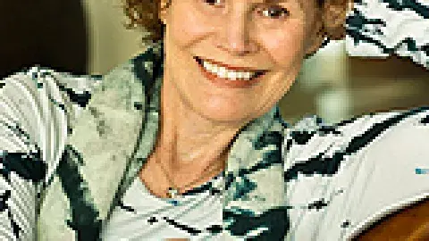 Judy Blume smiling sitting in a chair