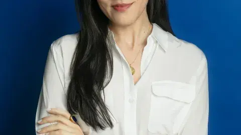 Sloane Crosley with her arms crossed against a bright blue wall