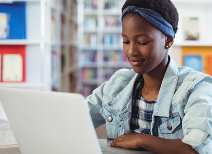 student sitting at the library with her laptop